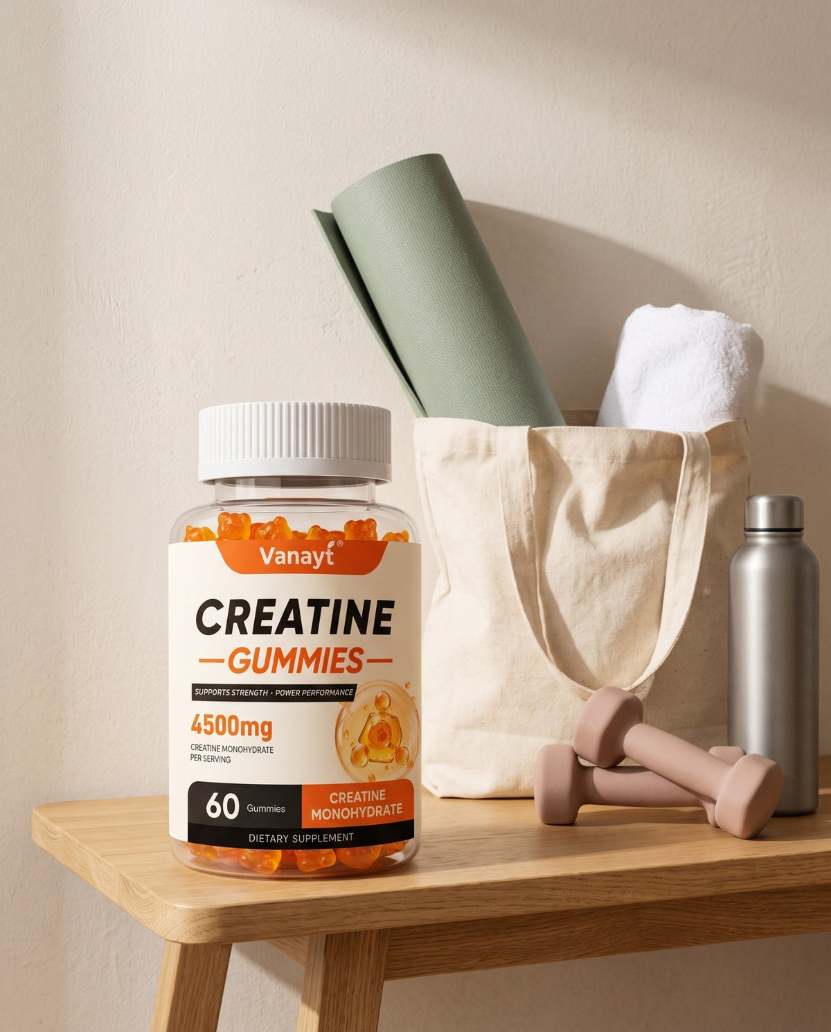Creatine gummies bottle beside a canvas tote, a rolled sage mat and blush dumbbells